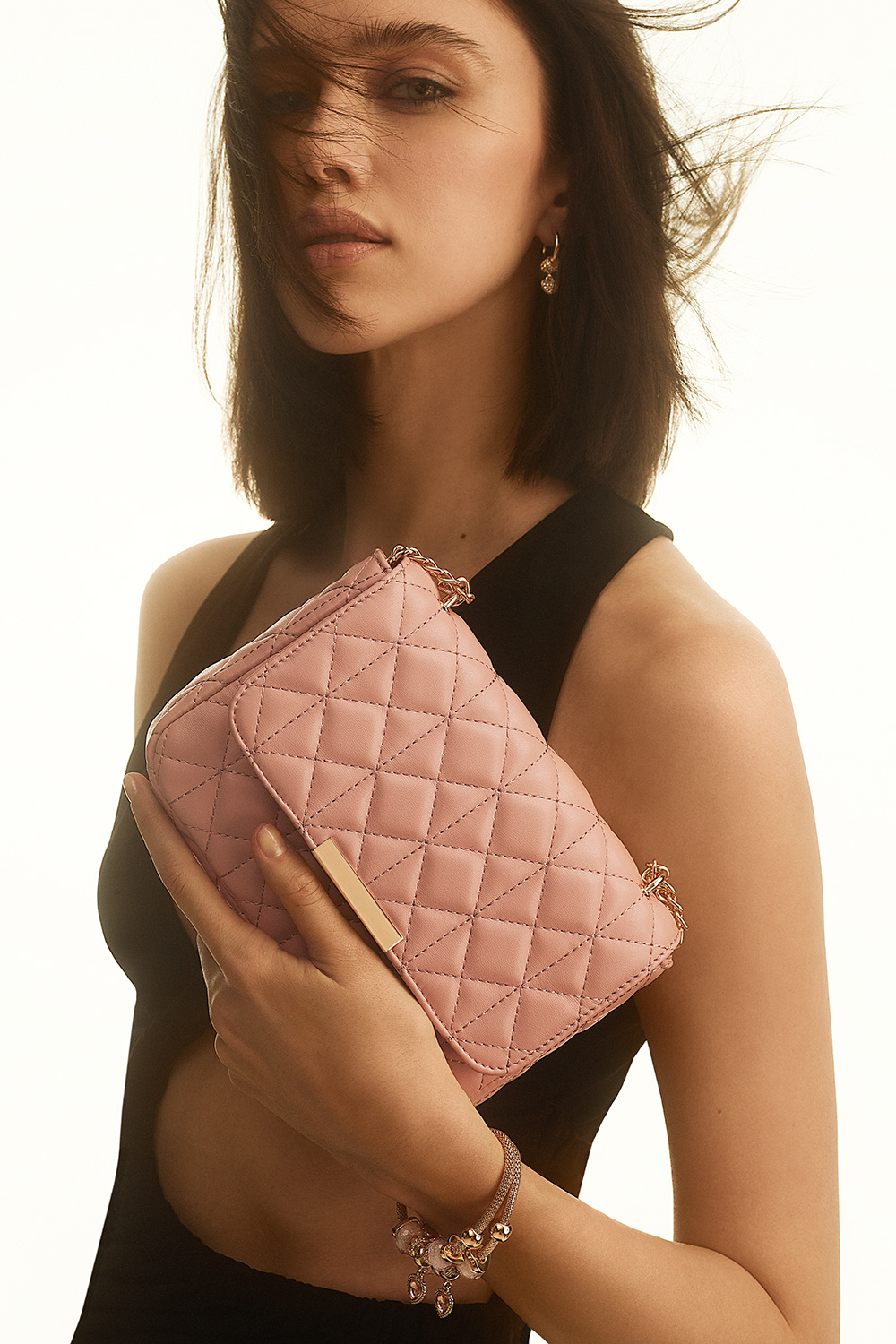 Rosa veske med quiltet design og gullfarget skulderrem