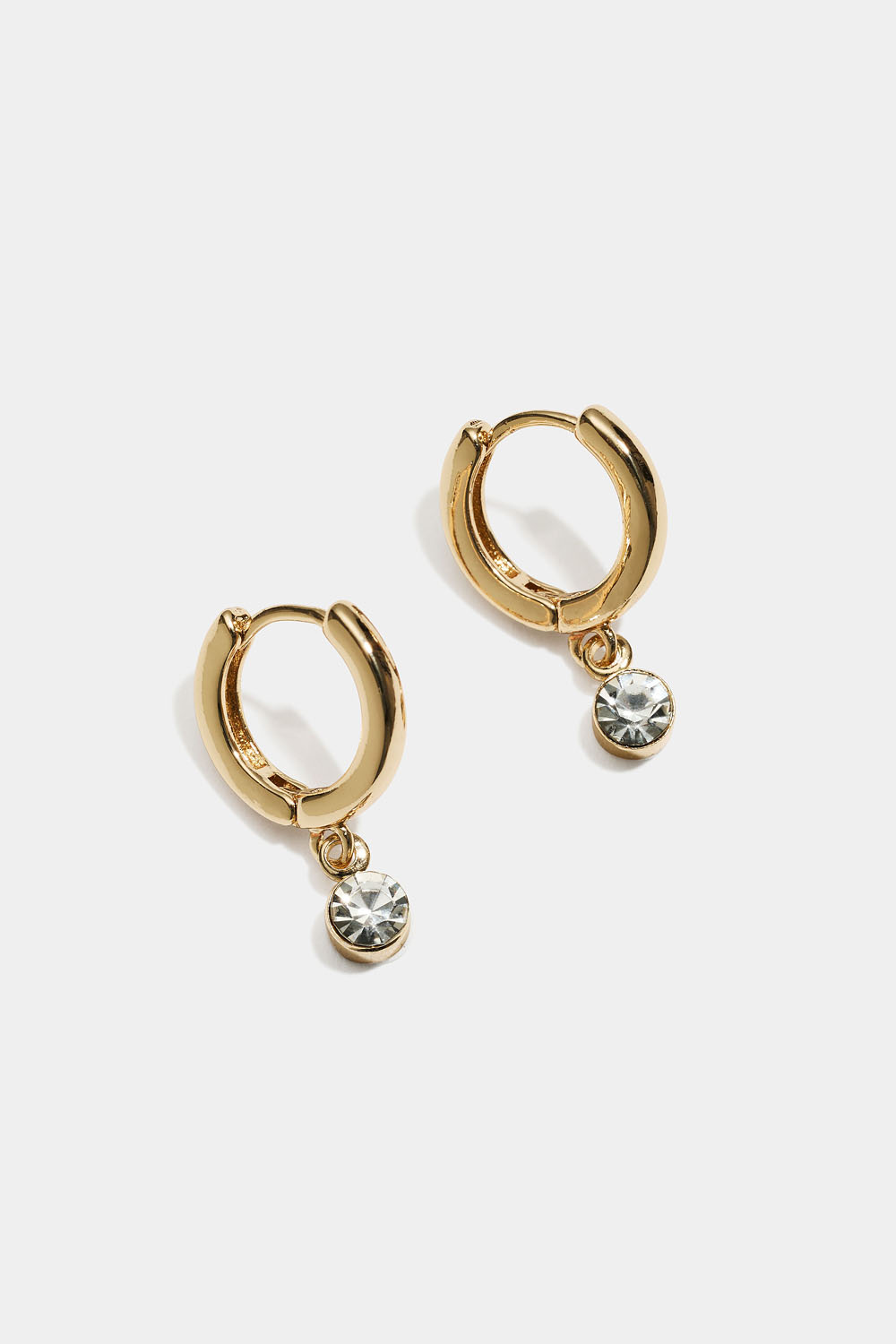 Små gullfargede øreringer med hengende glasstein