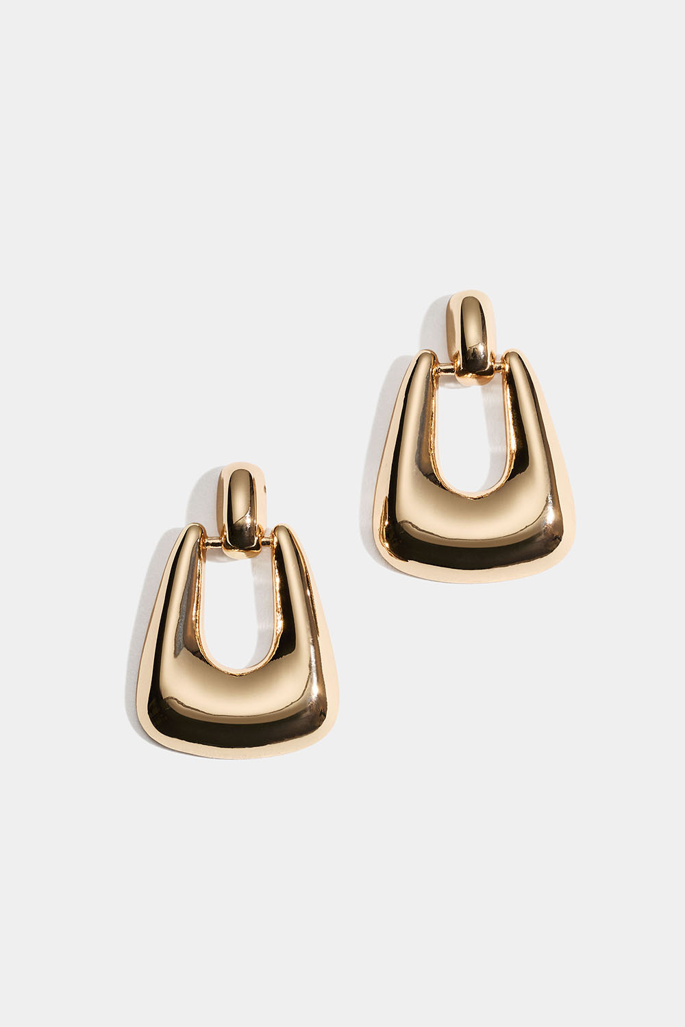 Gylne øredobber i blankt metall.