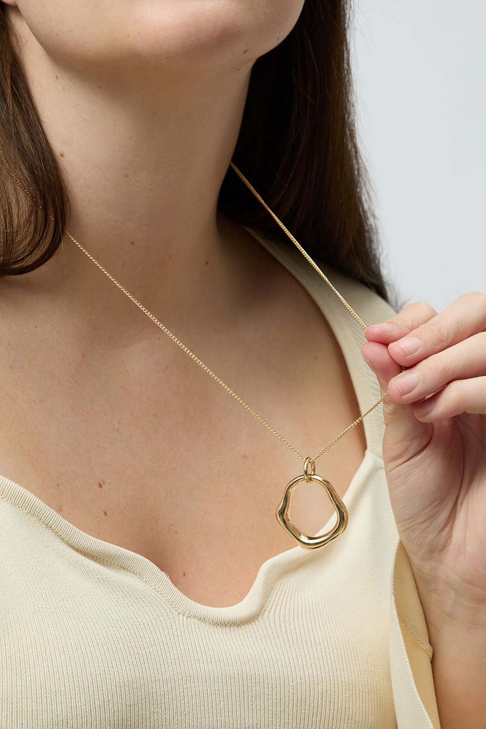 Gullfarget halskjede med rundt anheng i organisk form